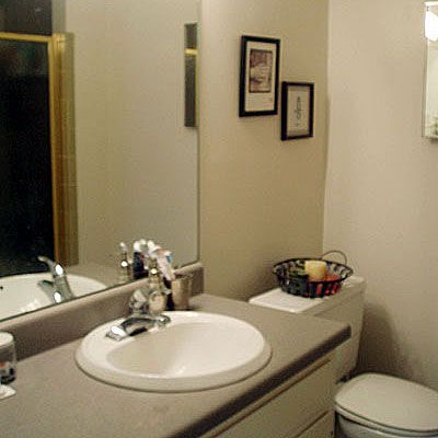 an outdated bathroom with gray formica countertops and a mirror before it is to be renovated