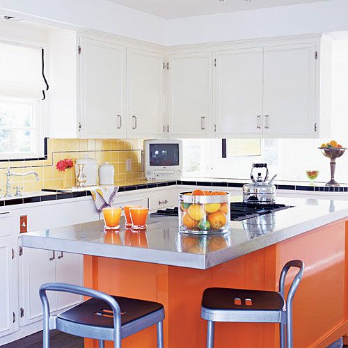 a bright, orange, modern kitchen island  with a steel countertop sits in the middle of this updated, vintage style kitchen