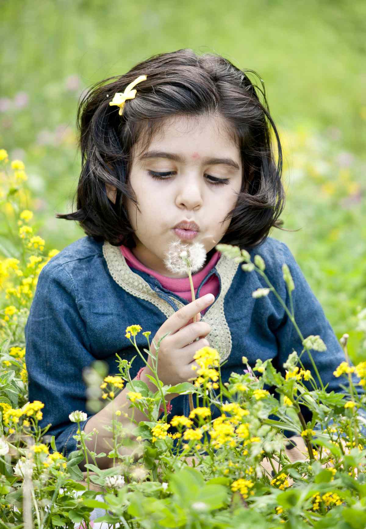 Girl blowing away dandelions.