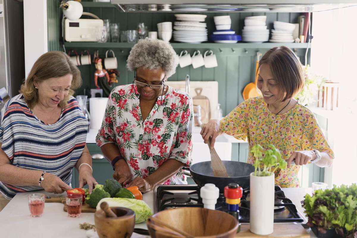 Active senior women friends cooking in kitchen