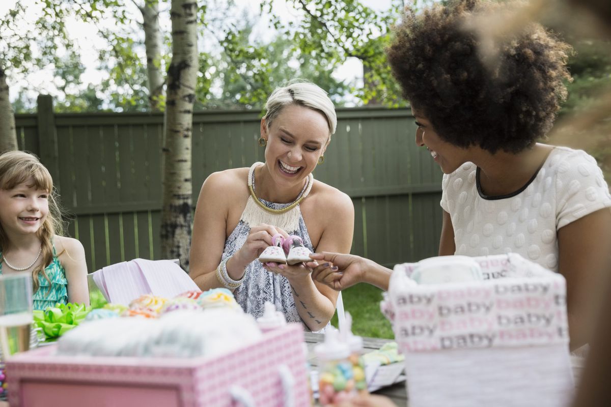 Women admiring tiny baby shoes at baby shower