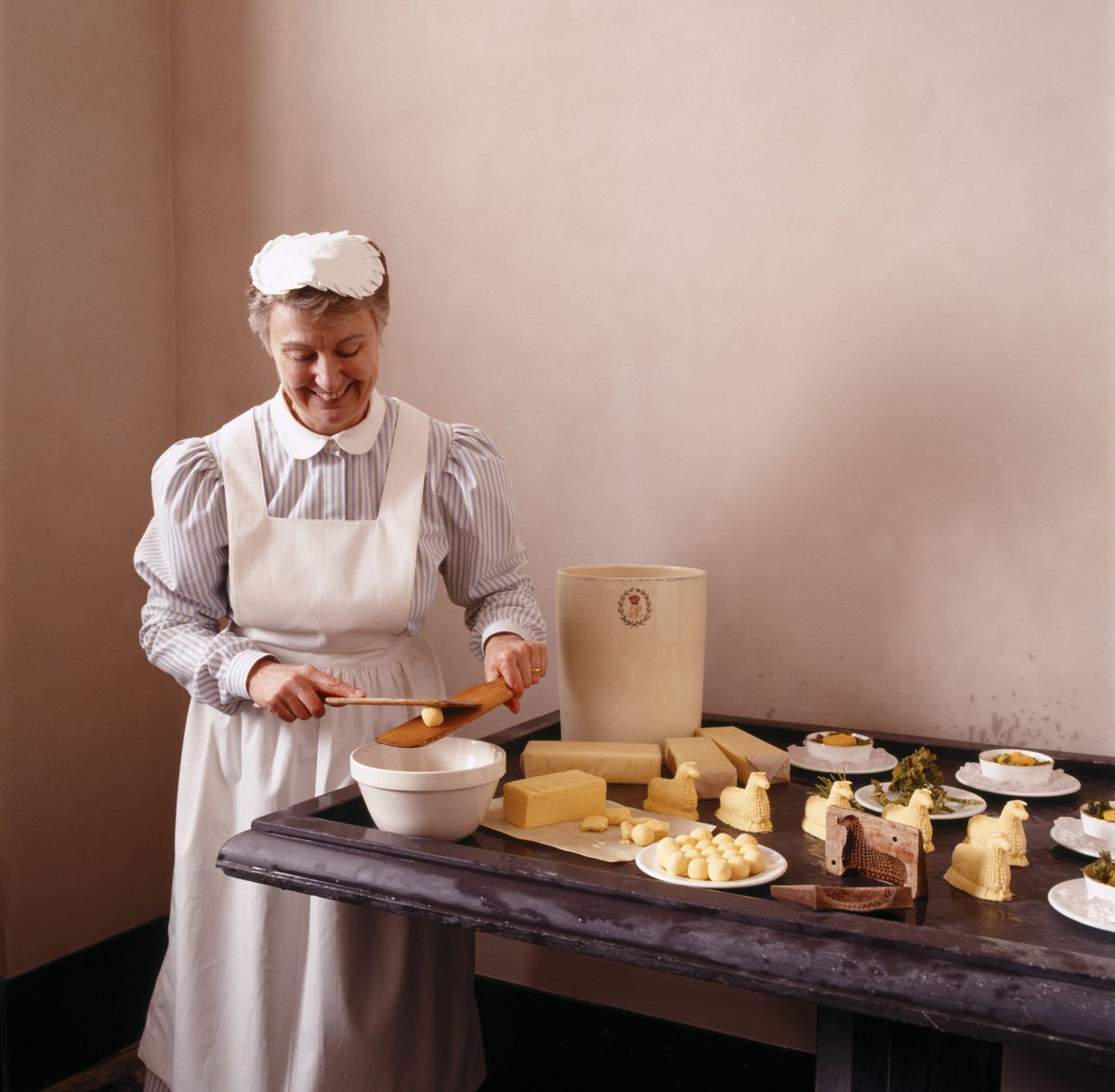 Woman Dressed in Victorian servant's dress, moulding butter in the Dairy Larder at Penrhyn