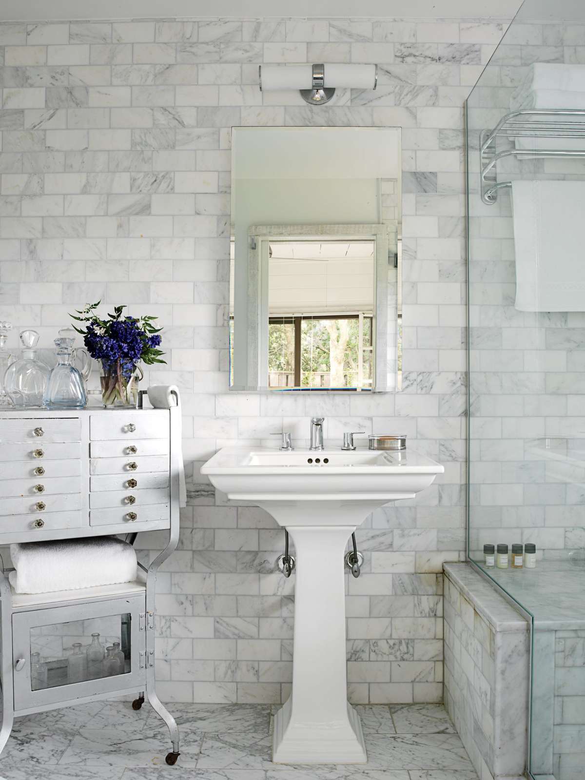 The floor and walls in this Fire Island bath are clad in Carrara marble (by Ann Sacks) tile to resist trapped moisture and tracked-in beach sand. The cool, monochromatic color scheme gives the room a soothing, spa-like feel.