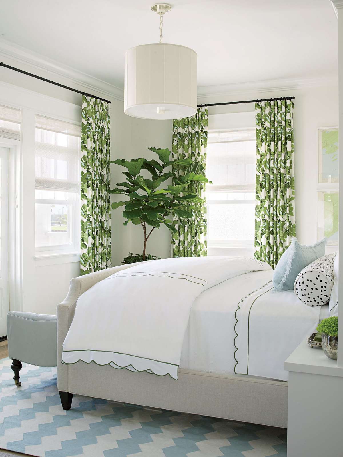 The color scheme of our Coronado Showhouse master bedroom is inspired by the green fig leaf-patterned drapes, which have robin’s egg blue accents that are repeated in the chevron dhurrie rug, leather settee, and fringed accent pillow.