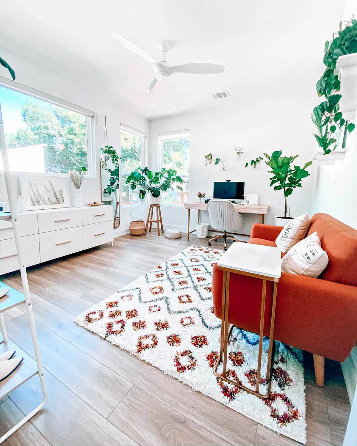 White home office with orange sofa and house plants