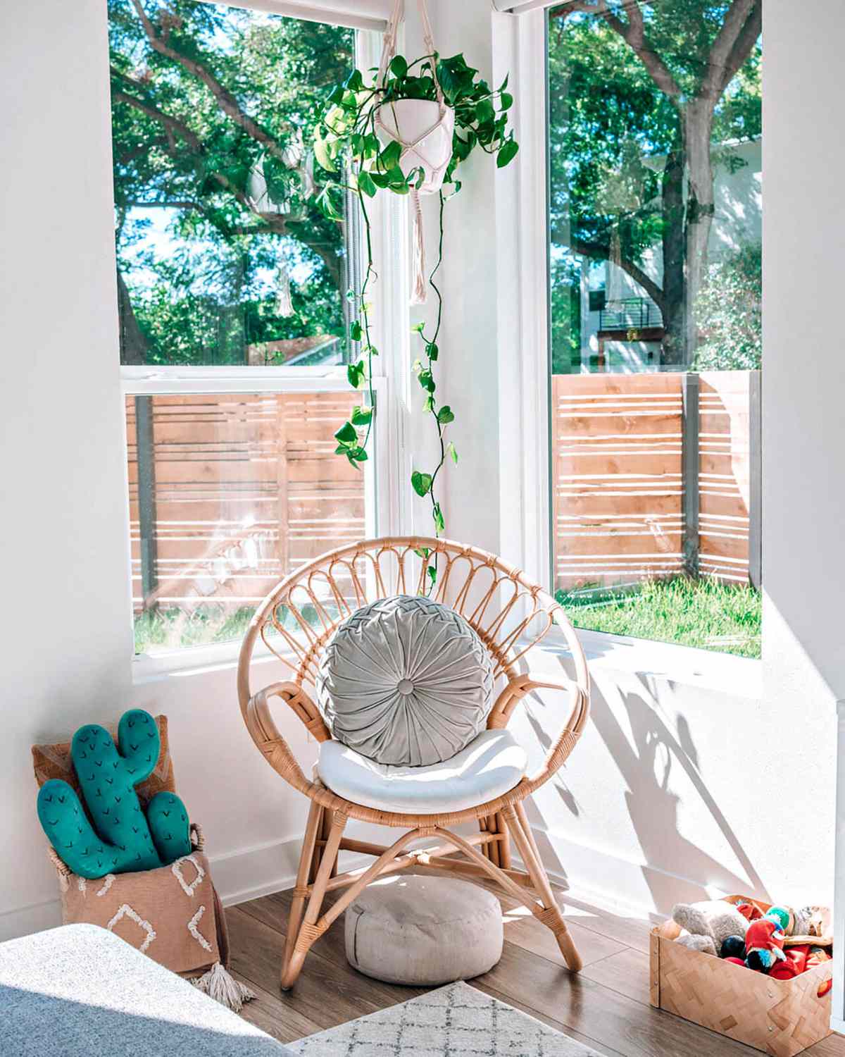 Rattan chair in corner of white living room with hanging plant above