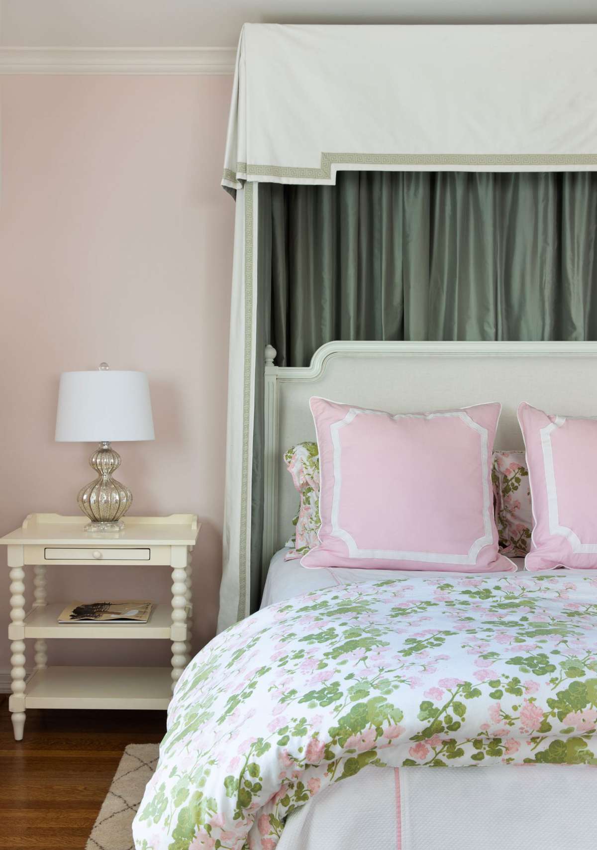 bed with floral bedspread and pink pillows