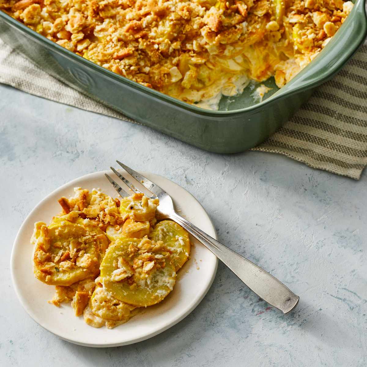 squash casserole on a plate with a casserole dish behind it