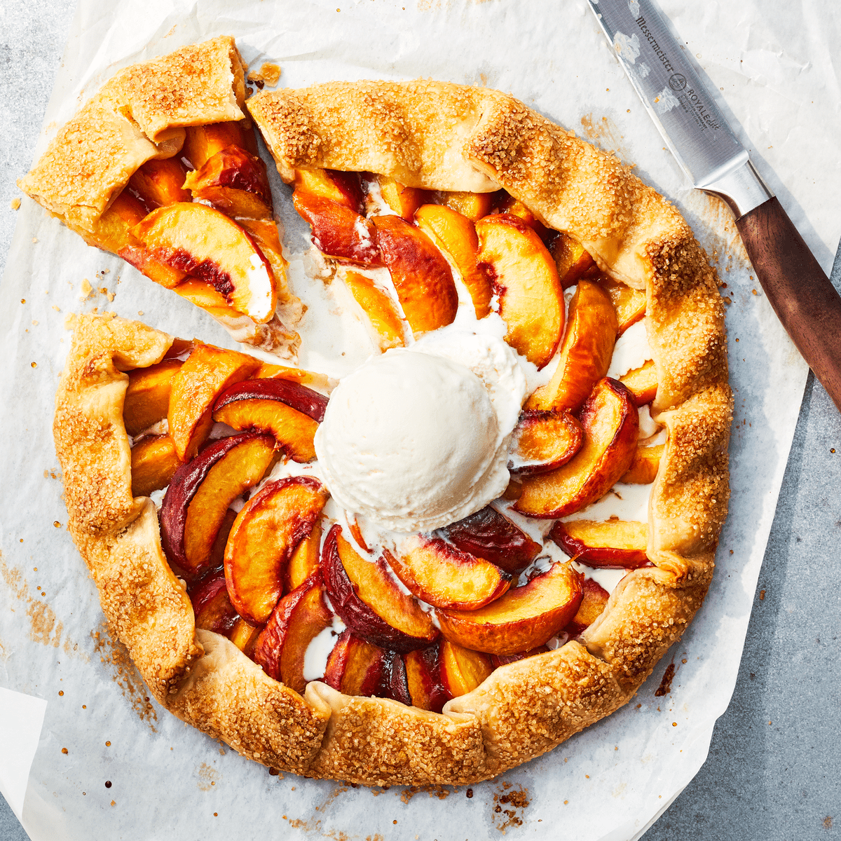 Gingered Peach Galette on parchment paper with a knife