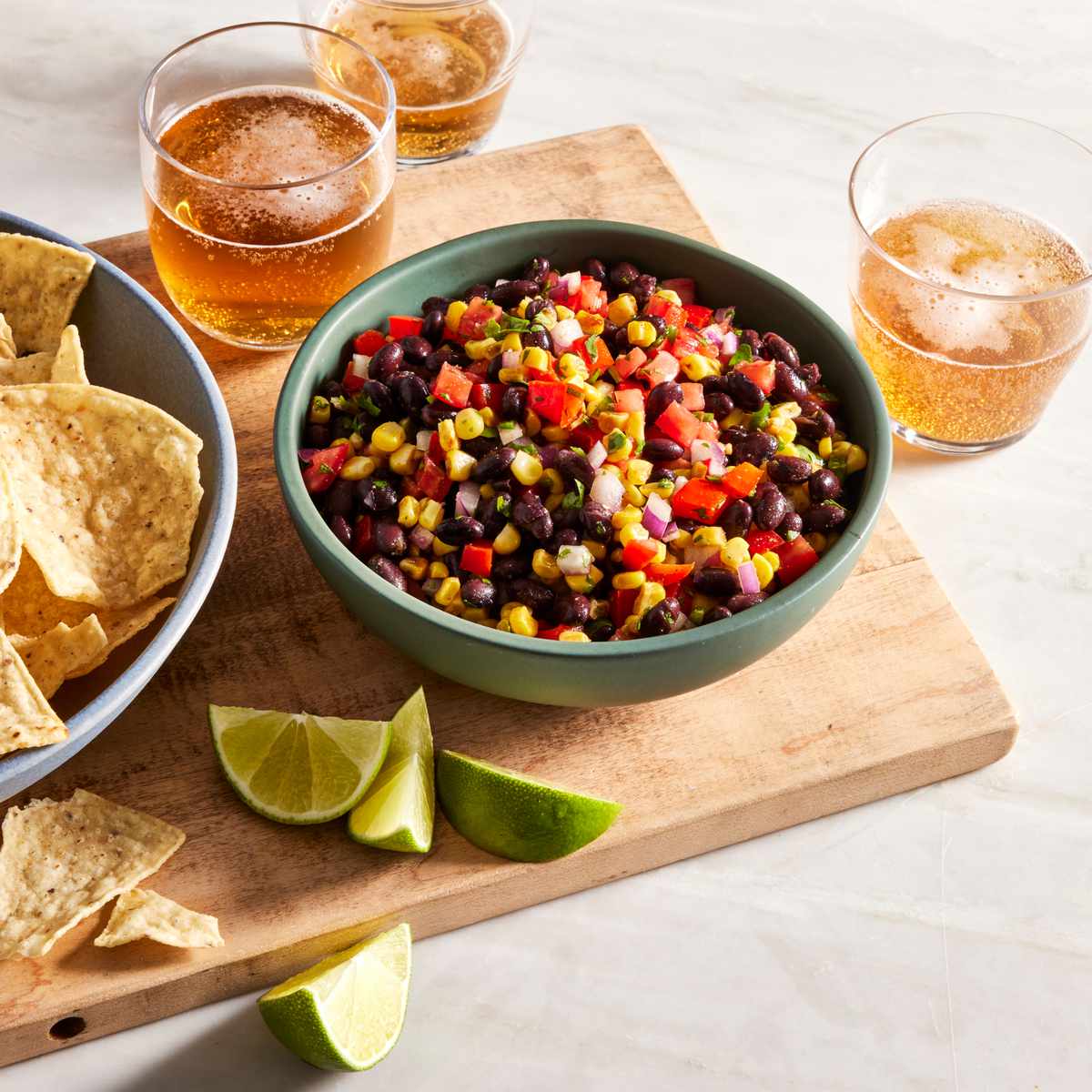 black bean and corn salsa in a bowl with a bowl of chips and some beer