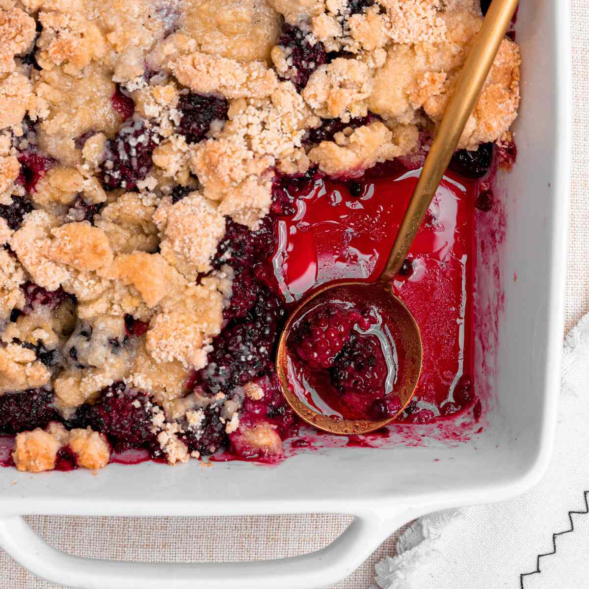 blackberry cobbler in a pan with a scoop missing