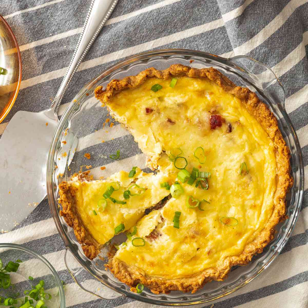 a pie dish of quiche lorraine with a slice missing