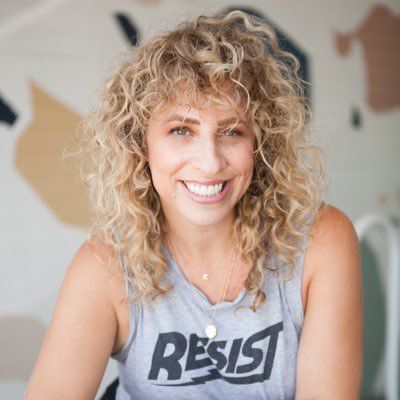 a woman with blonde curly hair smiles at the camera