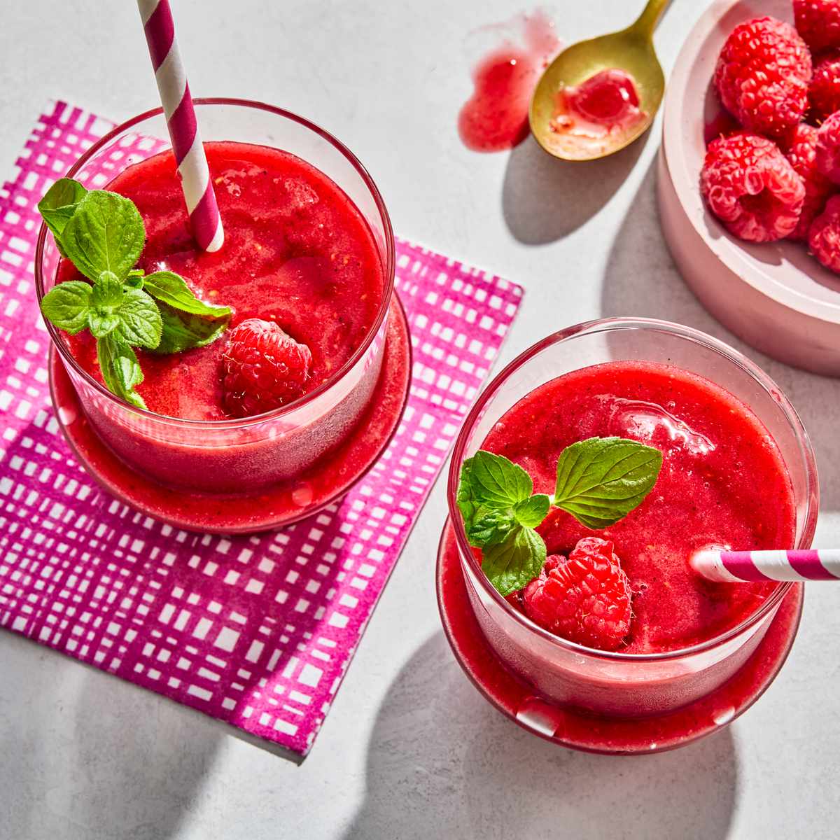 Frozen Raspberry Lemonade in two glasses with a bowl of raspberries