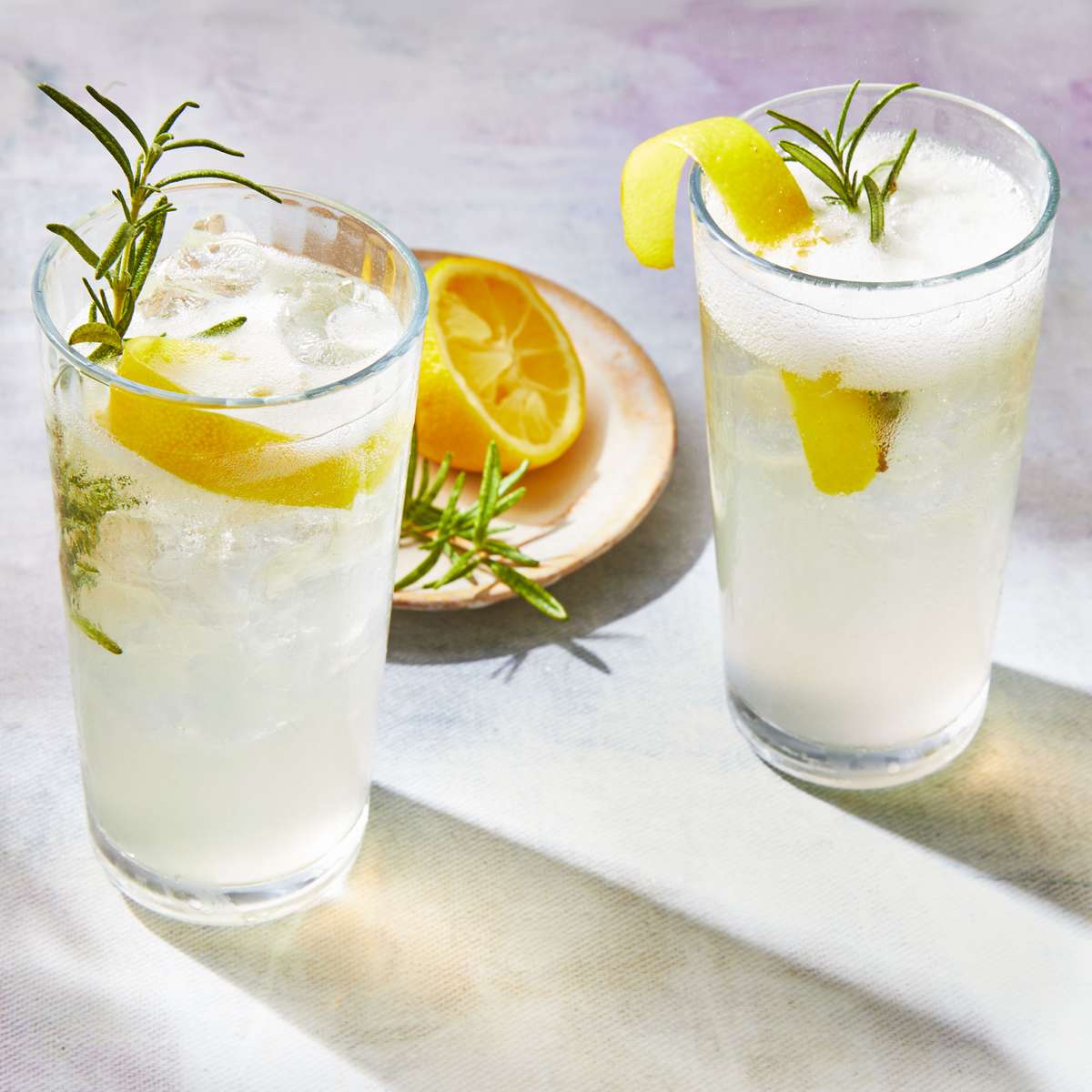 two glasses of cocktail with lemon and thyme garnishes