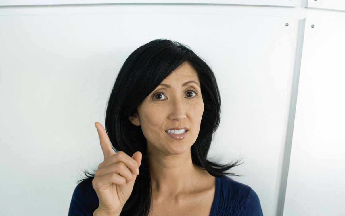 Woman holding up finger, looking at camera