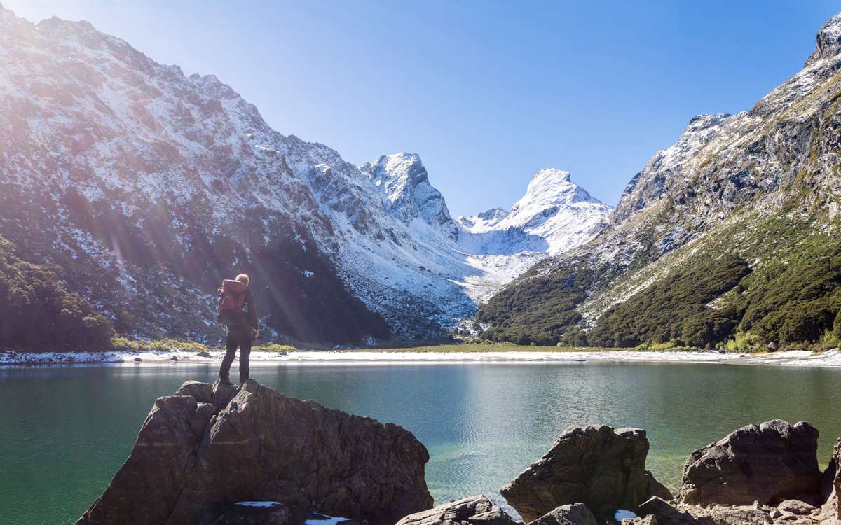 A hiker stands on a rock near Lake Mackenzie, in Fiordland National Park, New Zealand.