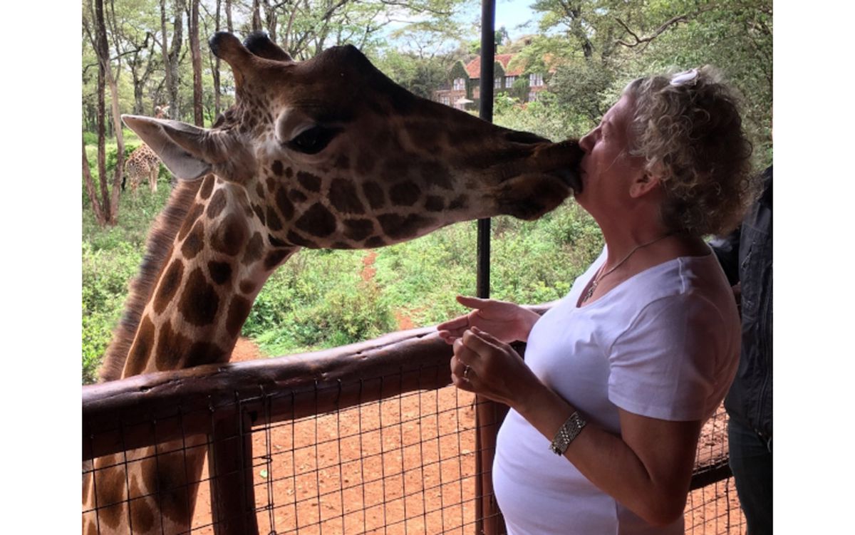 Debbie Campbell kissing a giraffe