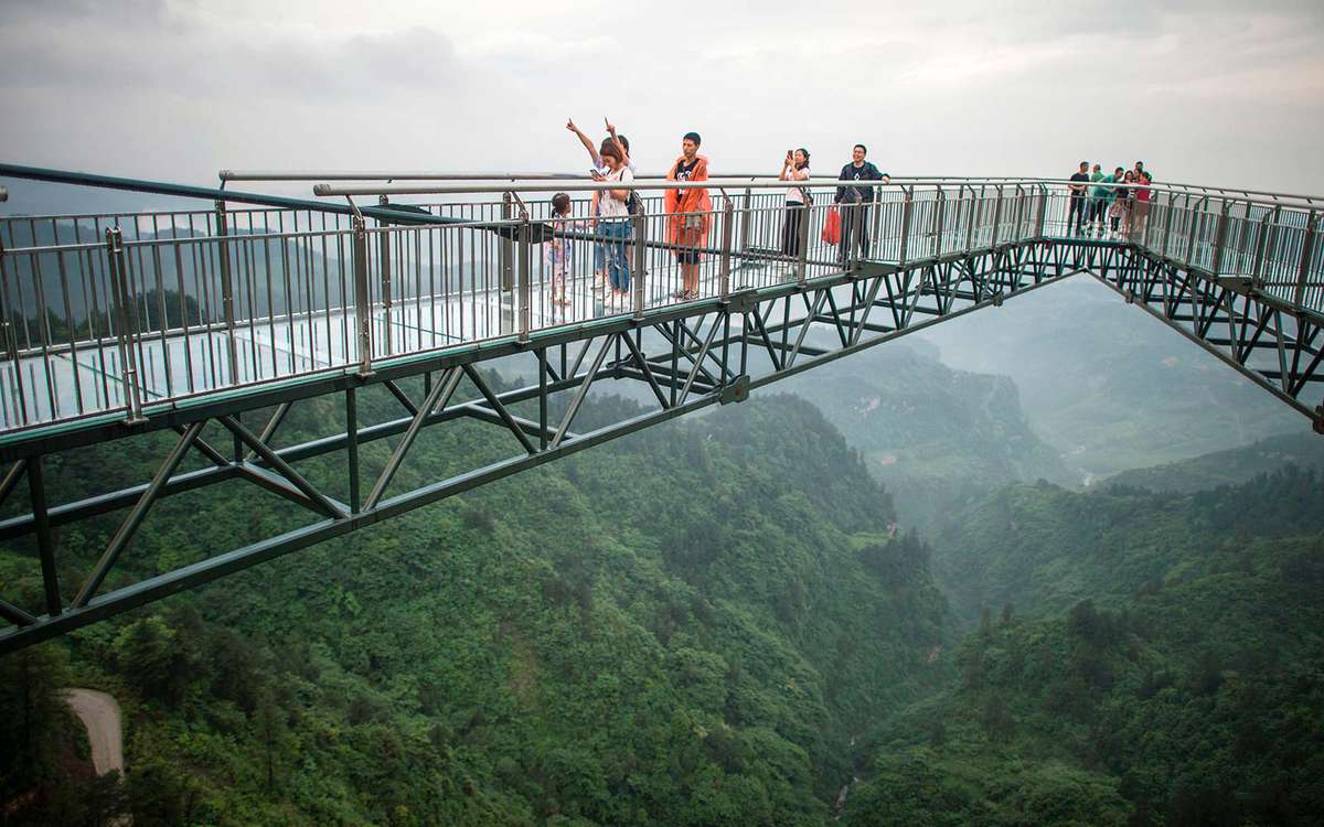 Tourists look on from a glass-bottomed skywalk.