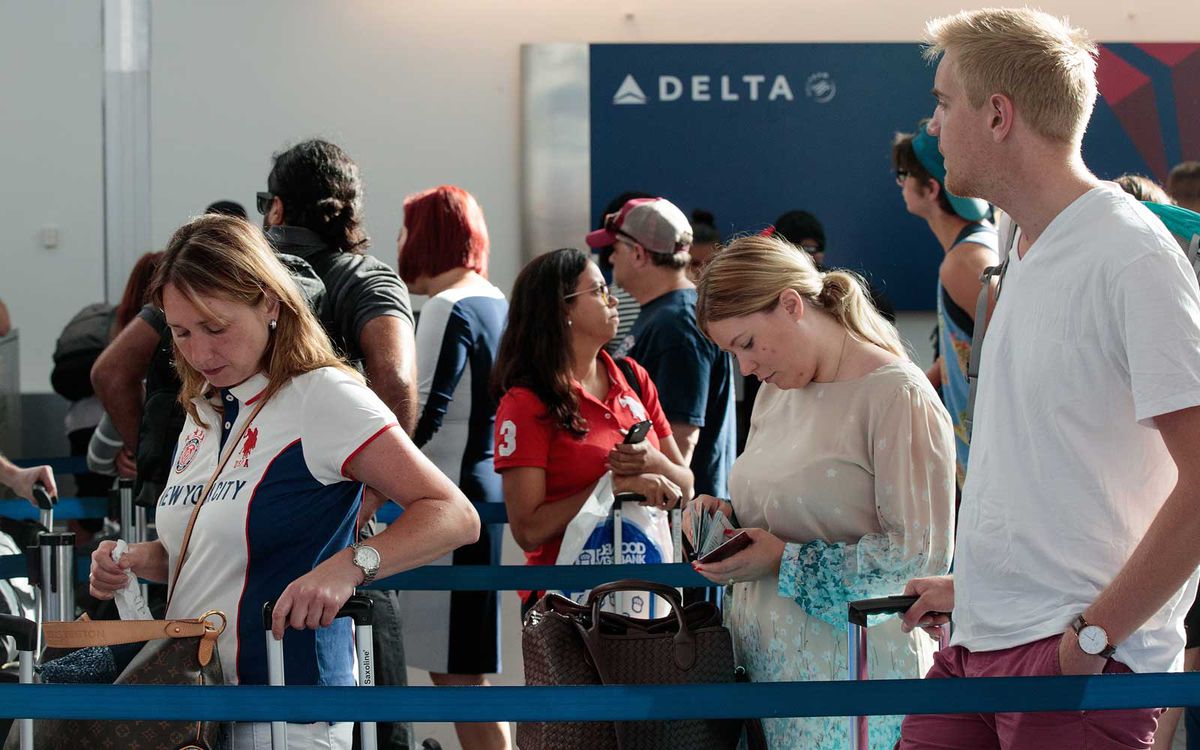 Travelers wait in line at the Delta check-in counter at LaGuardia Airport