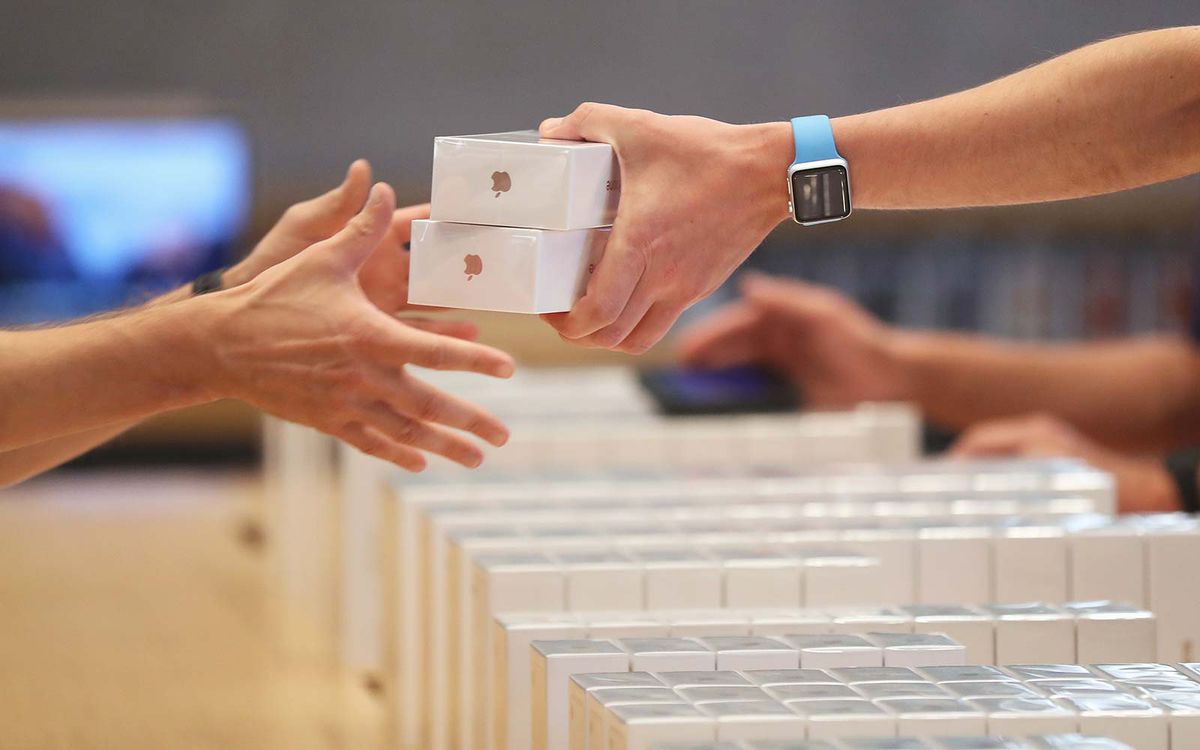 An Apple employee hands over Apple iPhone 7 phones on the first day of sales of the new phone at the Berlin Apple store