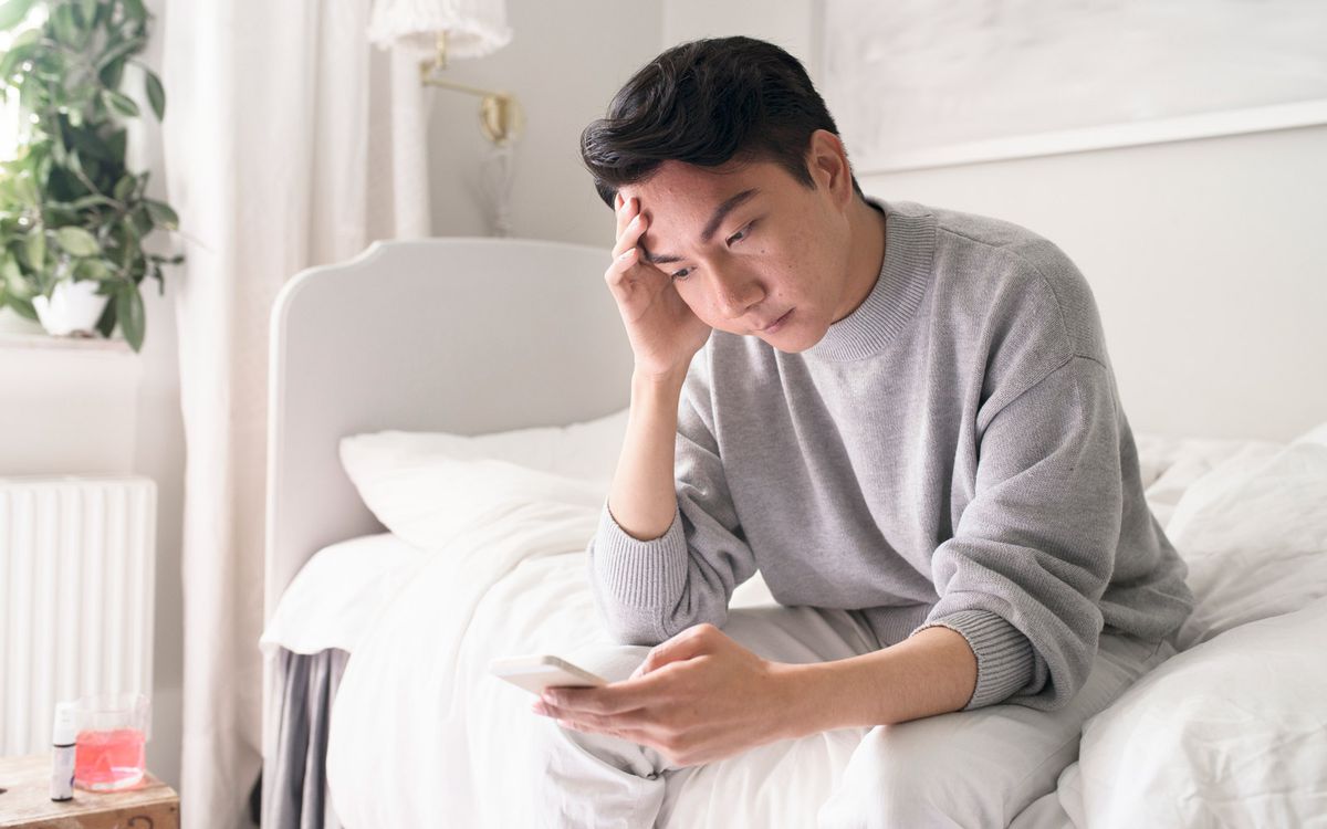 Man looking at phone in bed