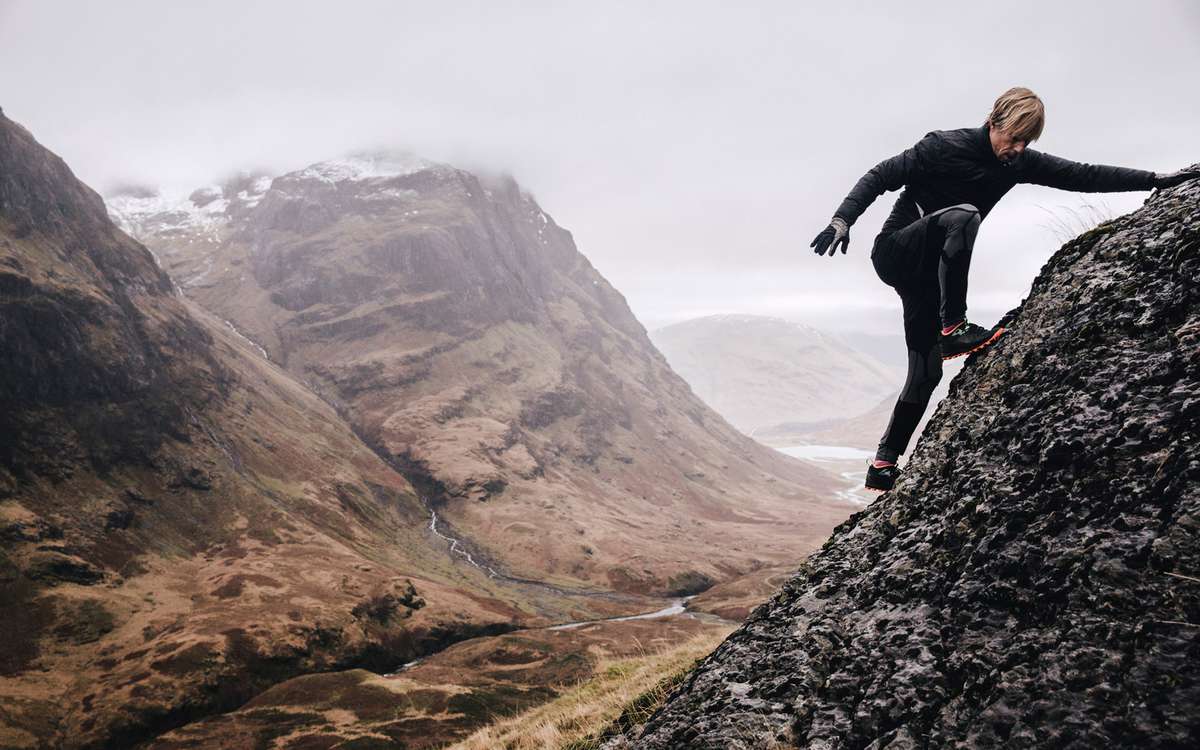 A free runner climbs a steep mountain rock face