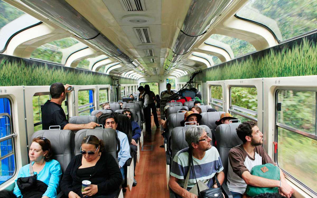 Tourists en route to Machu Picchu admire the scenery through panoramic windows of the Vistadome train