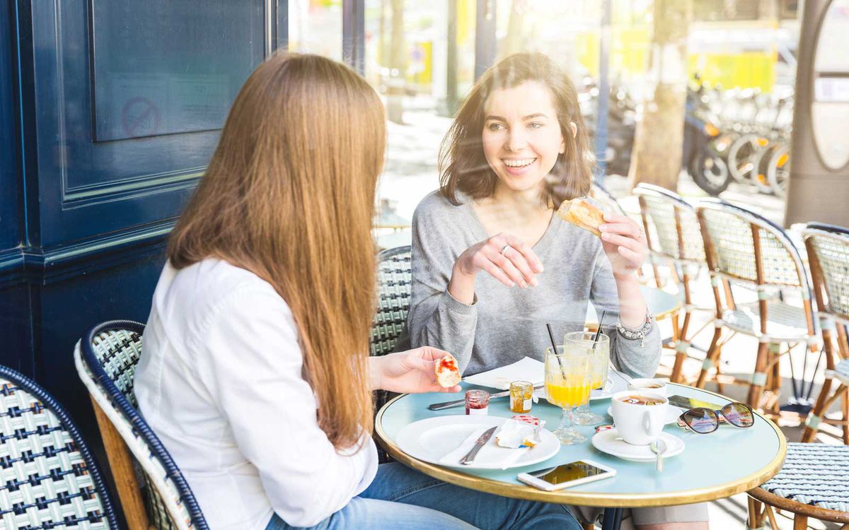 Two young female friends having breakfast at sidewalk cafe, Paris, France
