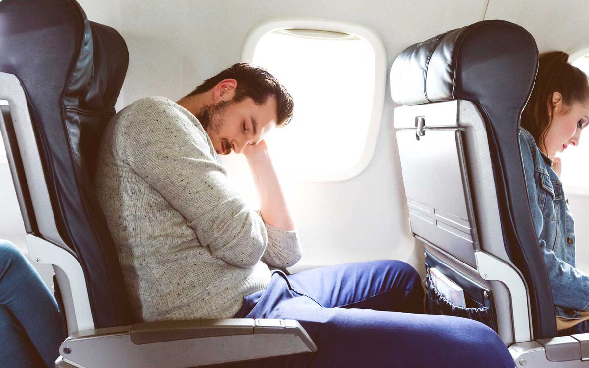 Young man sleeping during airplane journey