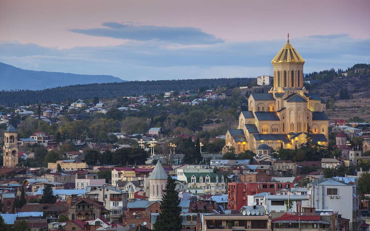 Georgia, Tbilisi, City and Tsminda Sameba Cathedral at dusk