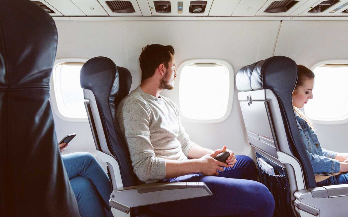 Young man sitting in airplane near window