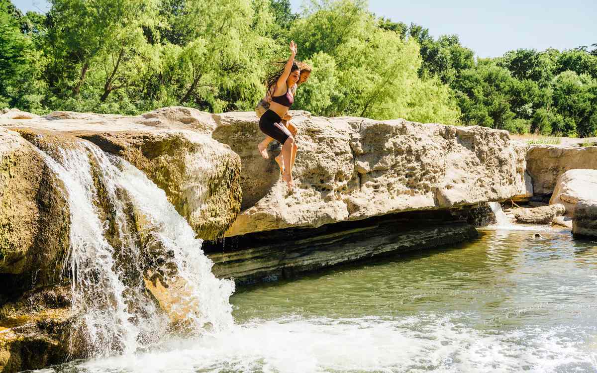 A couple jumps into a swimming hole in Austin, Texas.