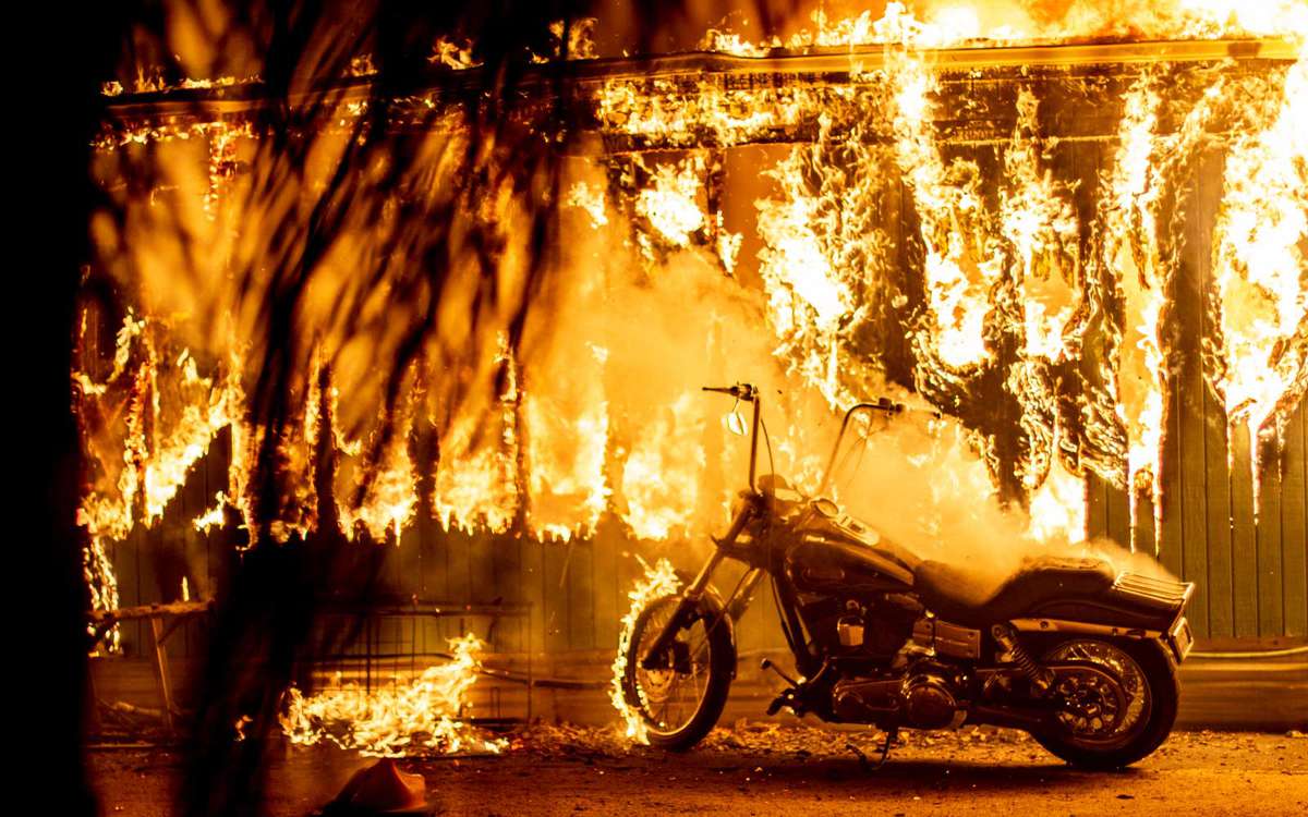 A structure and a motorcycle burn at an RV park during the Woolsey Fire in Malibu, California, November 10, 2018.