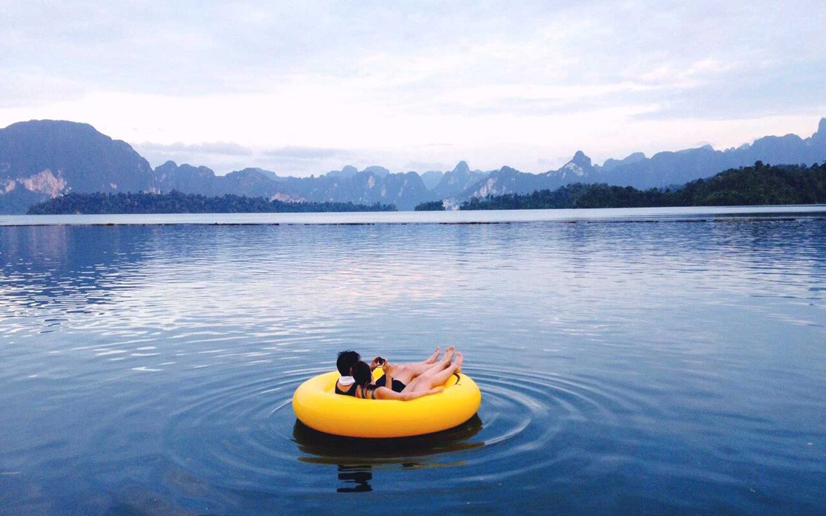 Couple On Inflatable Ring At Lake Against Sky