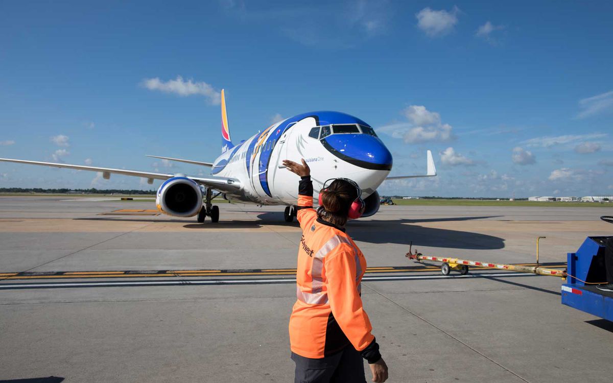 An employee can be seen helping taxi an aircraft.