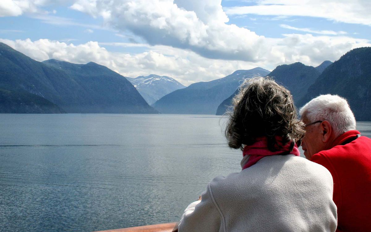 Couple enjoying  scenery of beautiful Norwegian fjords at start of cruise up whole Norwegian coast.