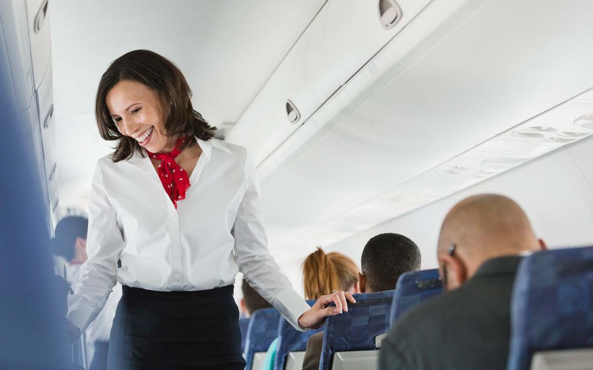Flight attendant talking to passengers in airplane