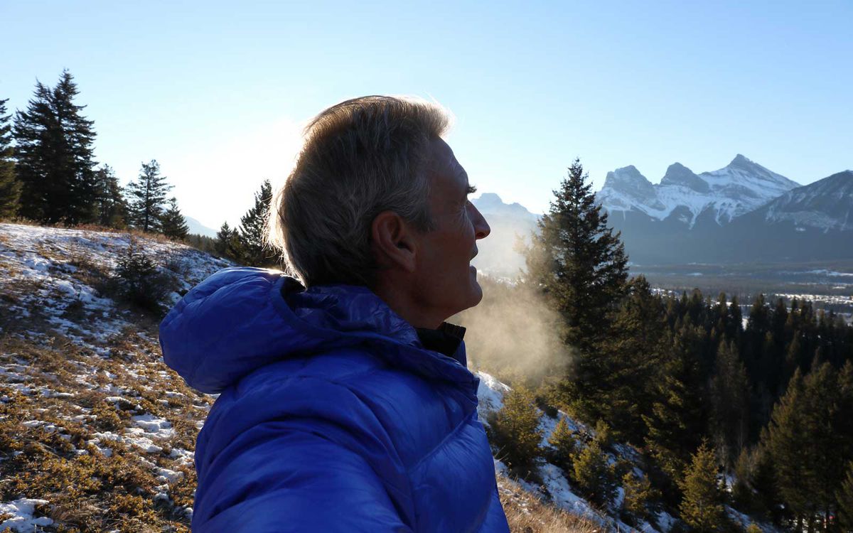 Man looks off to distant mountains from hillside on a cold winter day