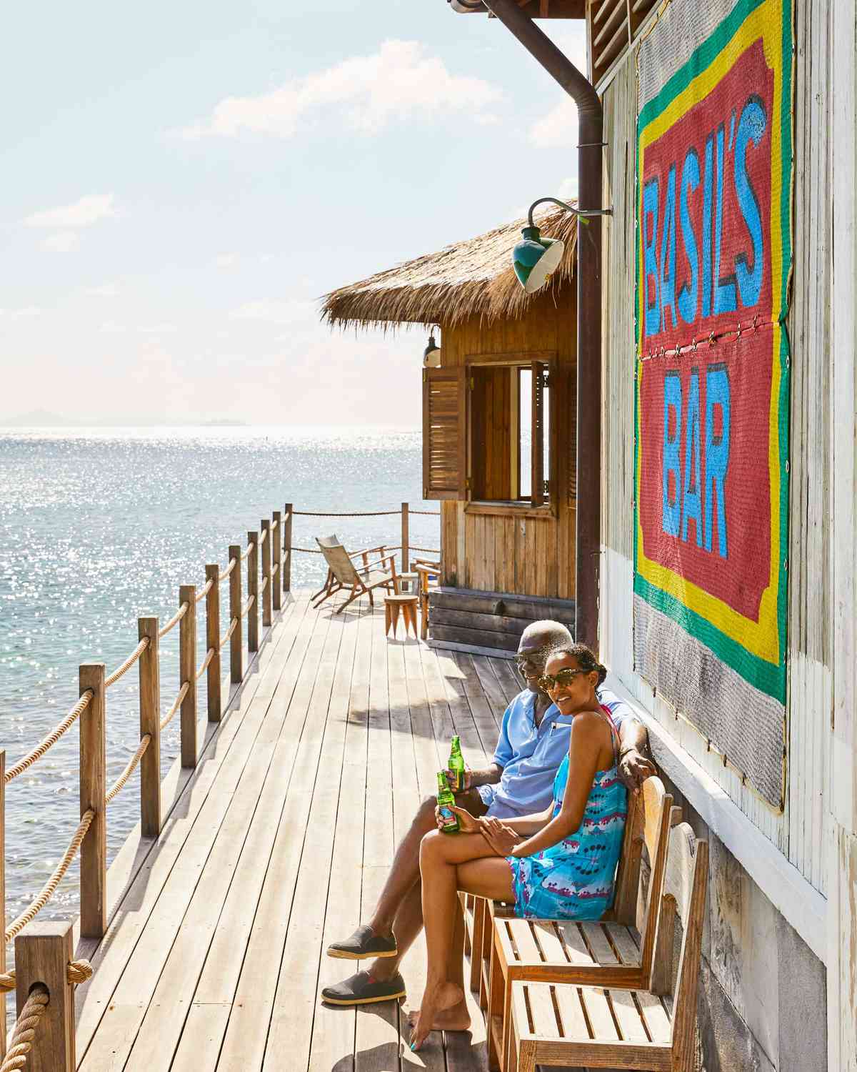Basil Charles and Gabija Mitchell sit by the water at Basil's Bar on the island of Mustique