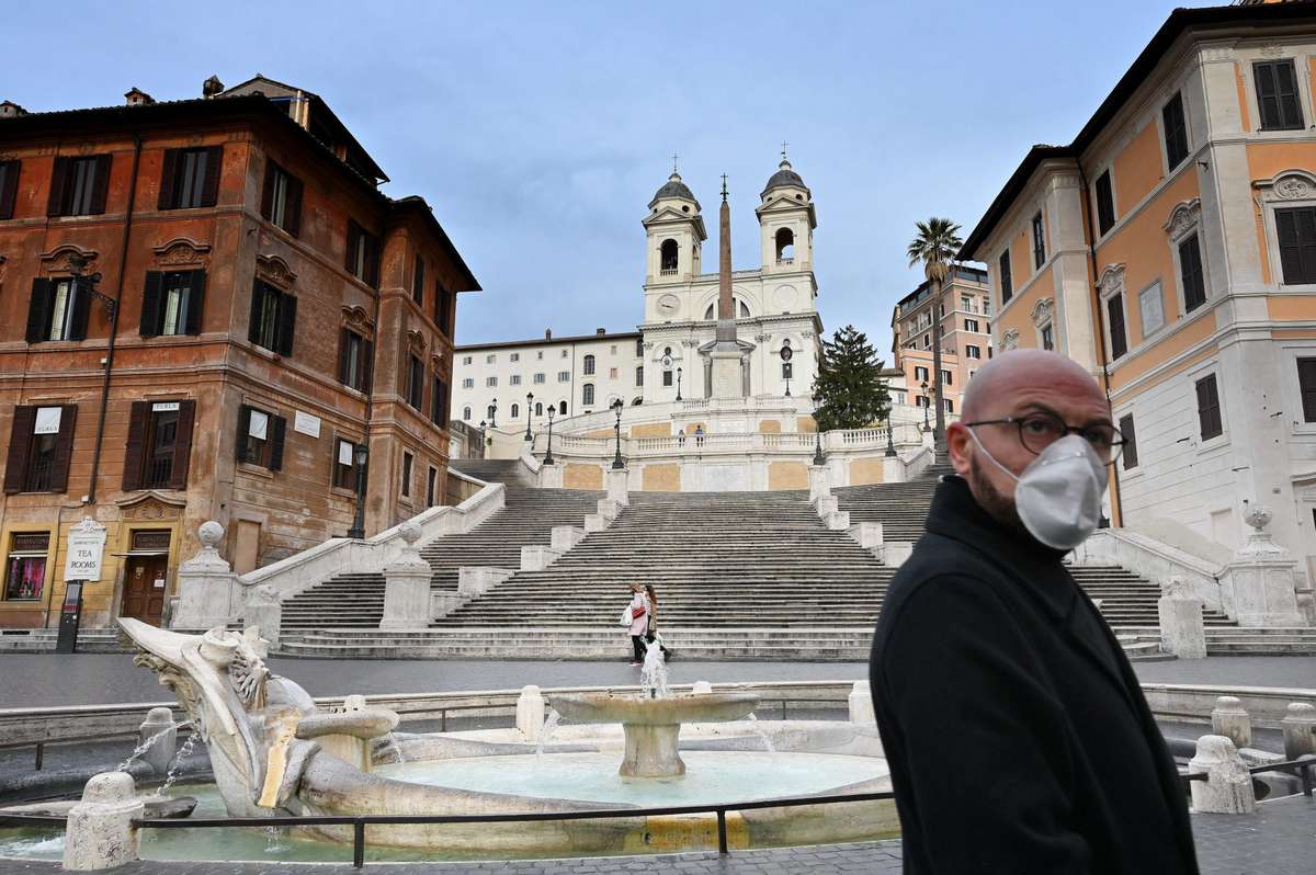 A man wearing a protection mask walks by the Spanish Steps