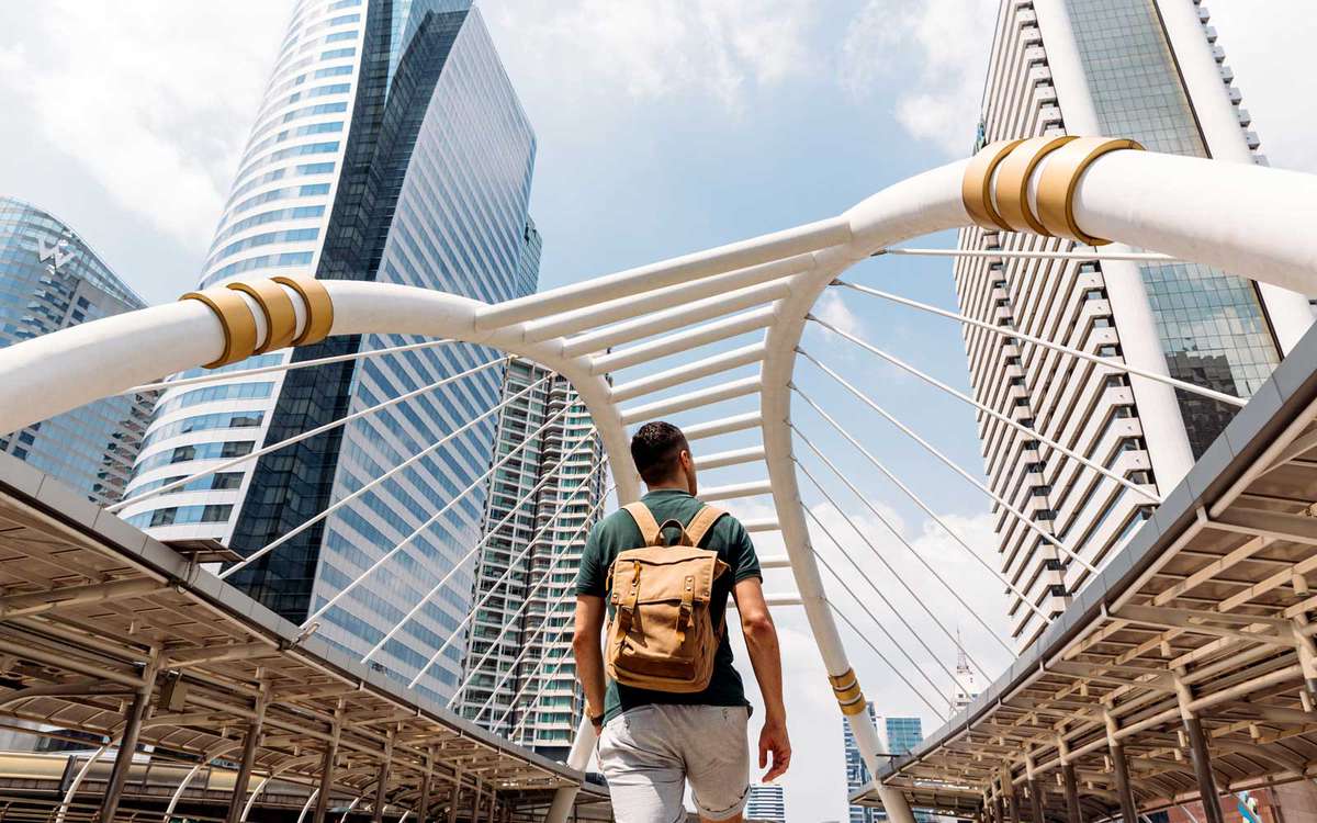 Vue arrière d'un homme avec sac à dos admirant les gratte-ciel modernes à Bangkok, Thaïlande
