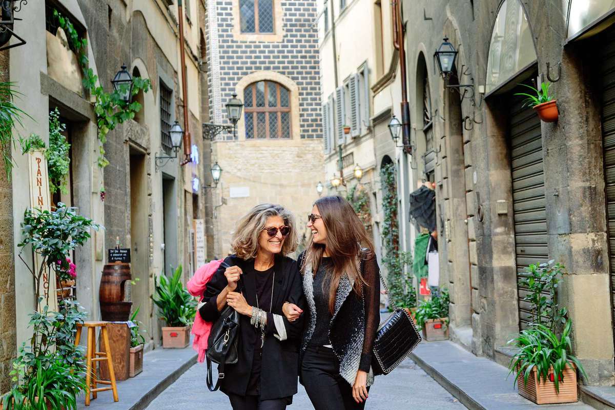 Mom and daughter walking in Tuscany cobble street