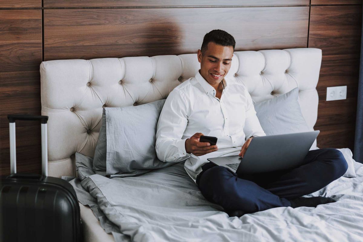 Cheerful man is using modern technologies in hotel room