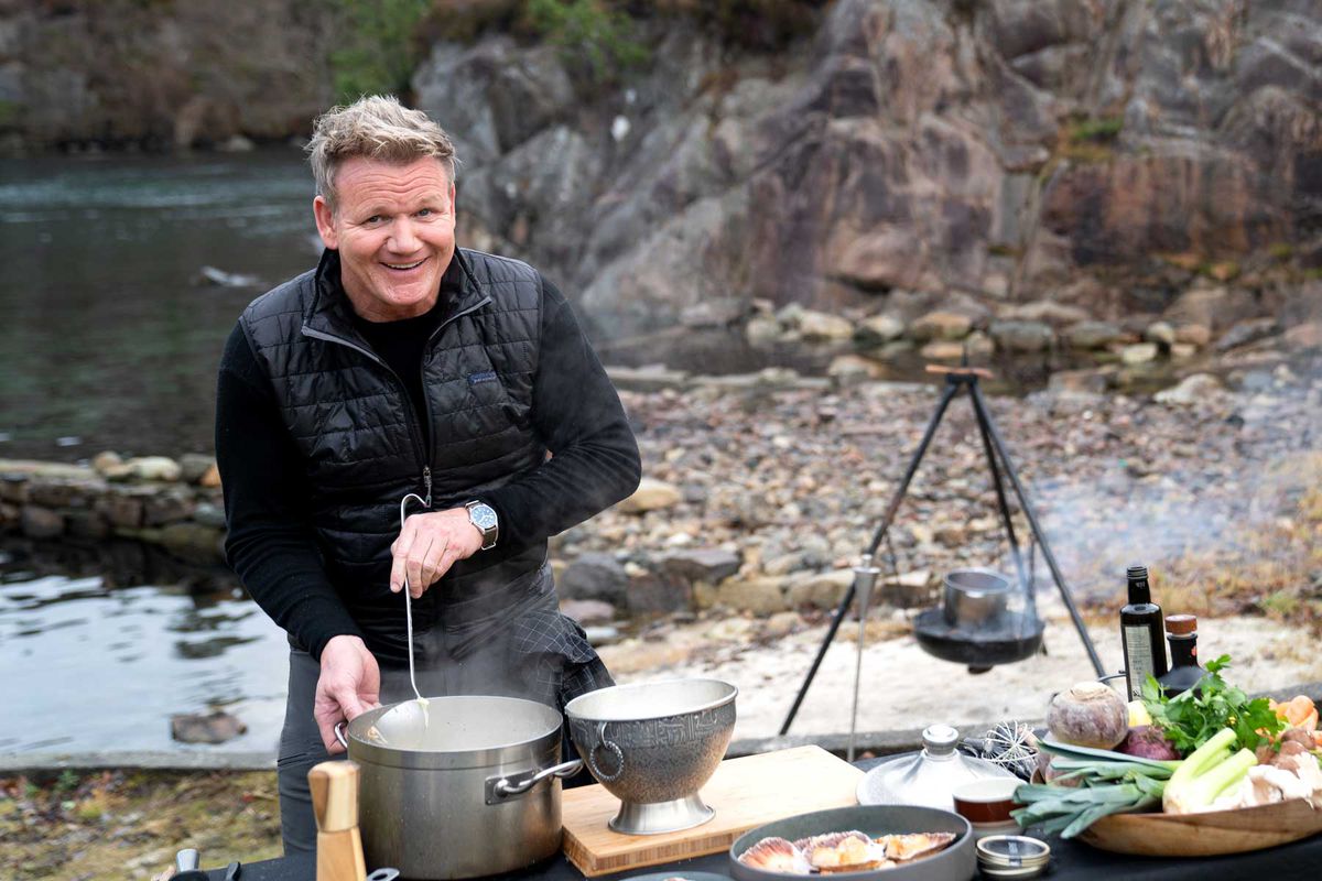 Chef Gordon Ramsay stirring a pot of chowder outside, on the shoreline of Vestry Island in Norway