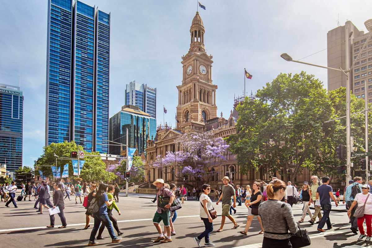 People walking along George Street in Sydney, Australia, with Sydney Town Hall in the background