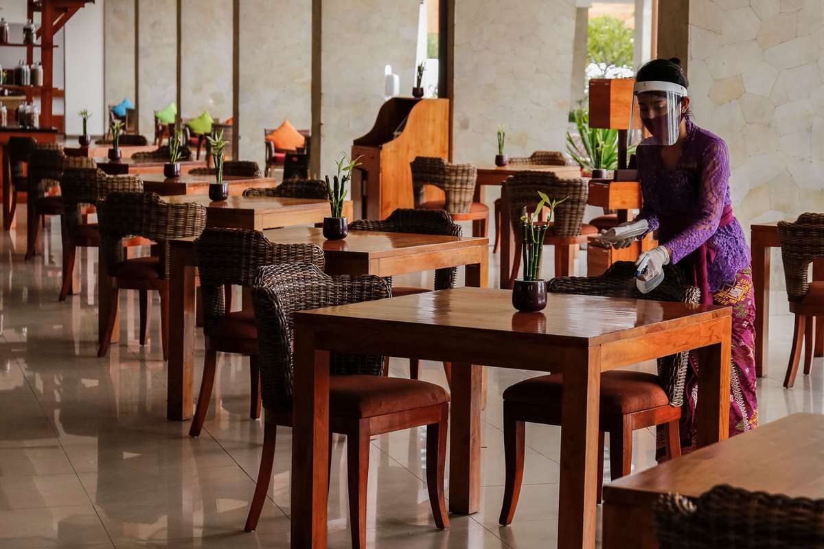 restaurant staff wearing PPE and cleaning tables