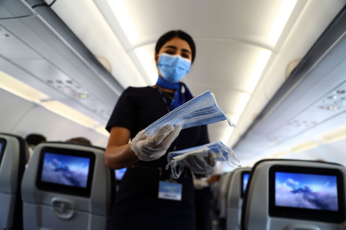 flight attendant face masks to passengers on an airplane