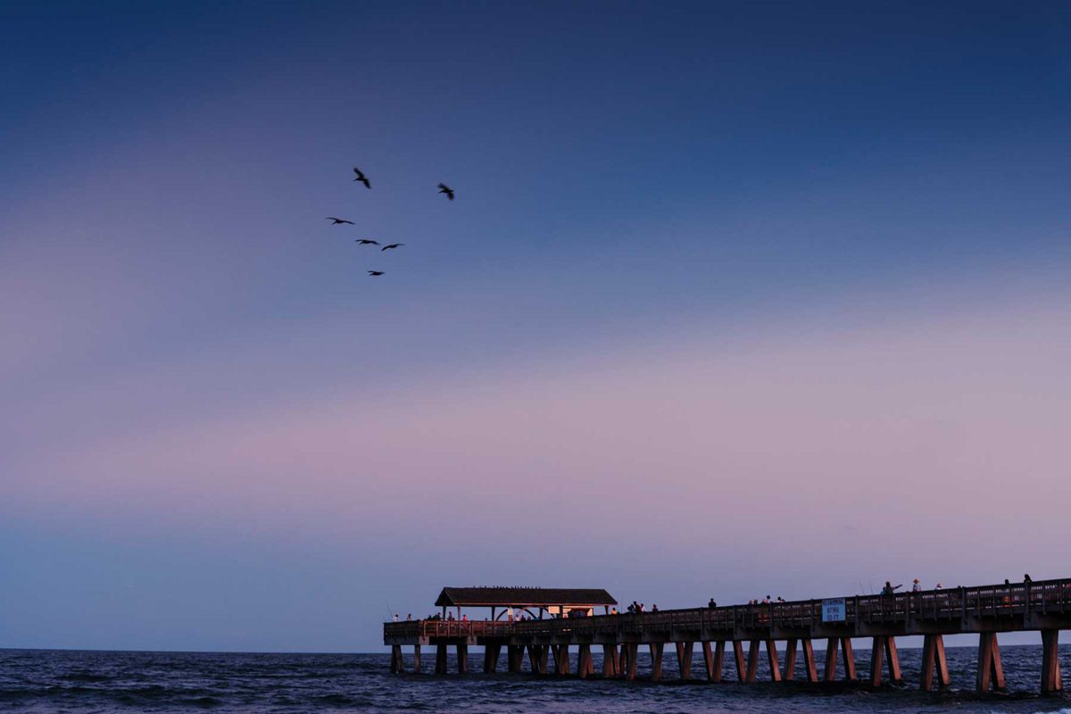 The fishing pier and Atlantic Ocean at Tybee Island in the purple light of the setting sun