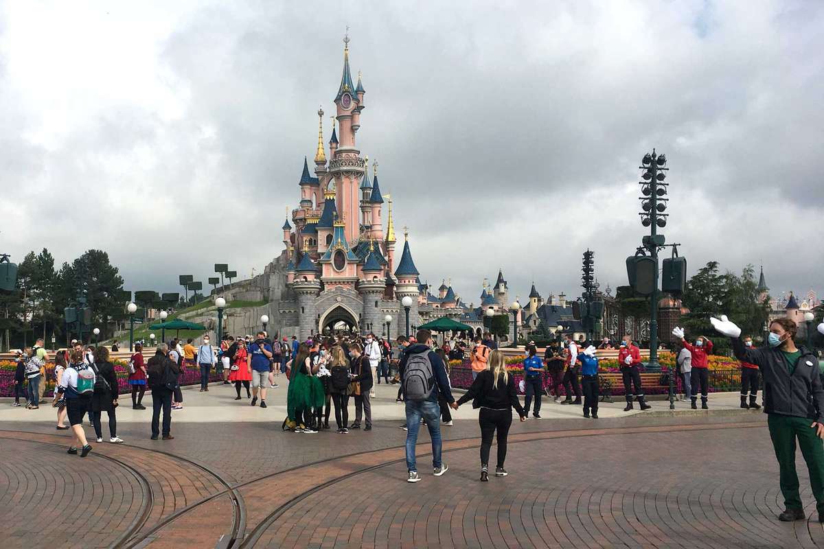 Visitors and staff wearing protective face masks, walk down the Main Street of Disneyland Paris in Marne-la-Vallee, near Paris, on July 15, 2020